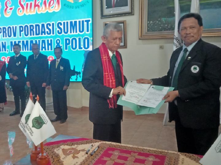 TERIMA NASKAH-Ketua Pengprov Pordasi Pacu Sumut Periode 2025-2029 Firdaus Tarigan SH MM CLA (kanan) menerima naskah salinan pelantikan dan pengukuhan dari Ketum PP Pordasi Pacu Teddy Soediro, usai prosesi yang dipusatkan di Aula KONI Sumut, Selasa (03/06/2025). Foto/mdc/asril tanjung